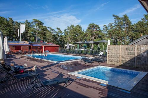 a swimming pool on a deck with two loungers at Ljugarn Semesterby in Ljugarn