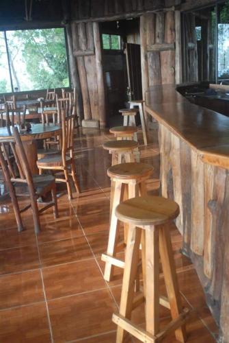 a bar with wooden stools and tables and chairs at Cabañas Don Camilo Albergue de Montaña in Cabecera de Cañas