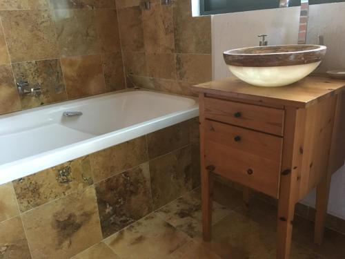 a bathroom with a tub and a sink on a wooden vanity at Refugio en el bosque de agua en Cuernavaca in Cuernavaca
