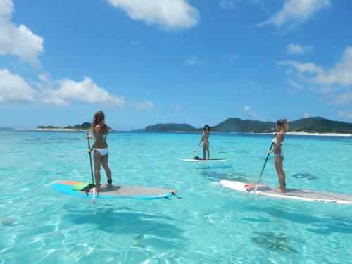 three women are standing on surfboards in the ocean at Oceans Cottage in Nago