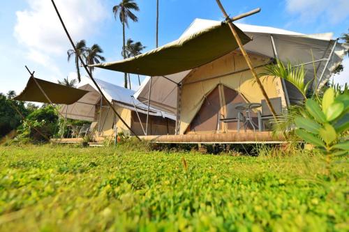 a building with a tent in a field of grass at Naivacha Tent Koh Mak in Ko Mak