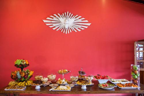 een tafel vol met eten tegen een rode muur bij Mundial Parque Hotel in Viçosa