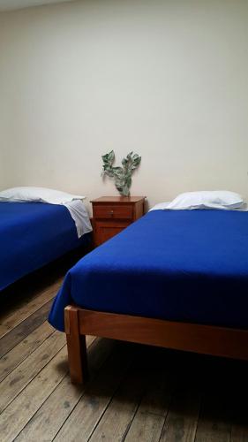 two beds with blue sheets in a bedroom at Casona Mollepata in Mollepata