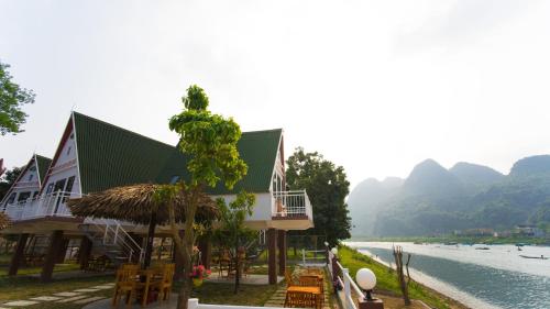 a building with tables and chairs next to a river at Carambola Bungalow in Phong Nha