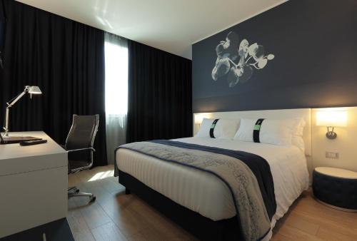 a hotel room with a bed and a desk and a bed at Holiday Inn Milan Nord Zara, an IHG Hotel in Cinisello Balsamo