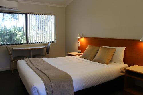 a hotel room with a bed and a desk and a window at The Pioneer Way Motel in Springwood