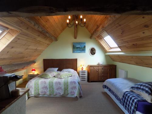 a attic bedroom with two beds and a chandelier at Gite des pâtissons in La Foret Du Parc