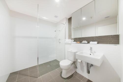 a white bathroom with a toilet and a sink at Abode Tuggeranong in Canberra