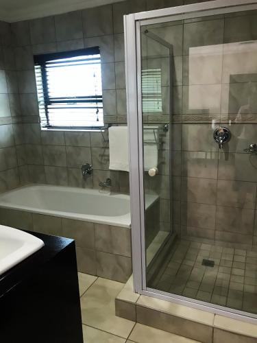 a bathroom with a shower and a tub and a sink at Ebandla Hotel & Conference Centre in Ballito