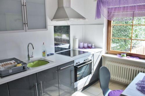 cocina con armarios blancos, fregadero y ventana en Ferienwohnung Guth en Wehr