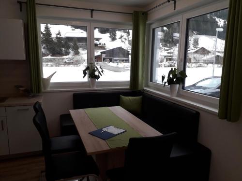 a dining room with a table and two windows at Apart Alpenflair in Sankt Leonhard im Pitztal