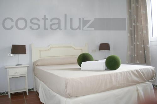 a white bedroom with a bed with green spheres on it at Apartamentos Aguadulce El Portil in El Portil