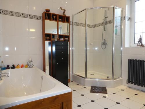 La salle de bains est pourvue d'une baignoire et d'une douche en verre. dans l'établissement The Cairn Residence, à Édimbourg