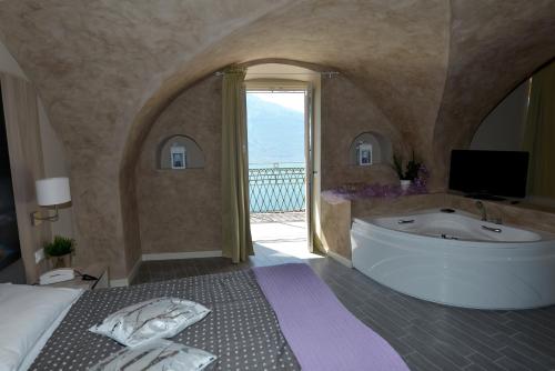 1 dormitorio con bañera grande y ventana grande en Hotel Miralago, en Tremosine Sul Garda