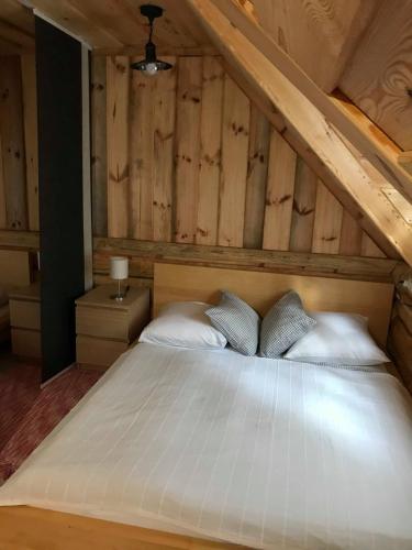 a bedroom with a white bed with wooden walls at Manka Kisrönkház in Ispánk