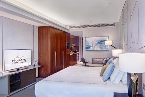 a hotel room with a bed and a television at Fraser Suites Dalian in Dalian