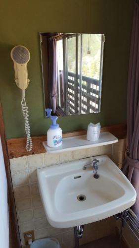 a bathroom with a sink and a mirror at Ryokan Maruya in Yufu