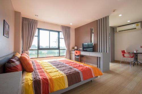 a bedroom with a bed and a desk and a television at Live at Home Sukhumvit 105 in Bangkok