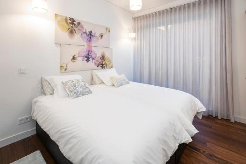 a white bedroom with a large white bed and a window at L Orangerie CA by Intiholidays in Vilamoura