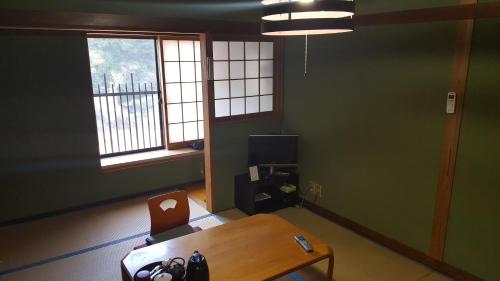 a room with a table and a chair and two windows at Ryokan Maruya in Yufu