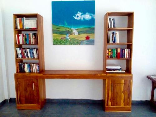 a wooden bench against a wall with two book shelves at Anuhas Airport Villas in Katunayake