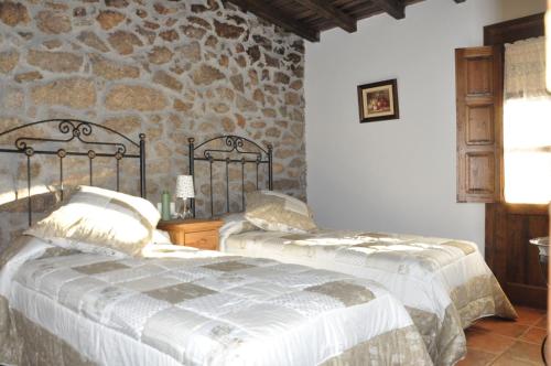 1 dormitorio con 2 camas y pared de piedra en La Luciérnaga, en Sorihuela