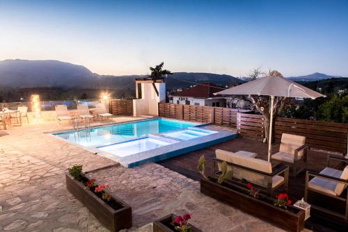 einen Pool mit einem Sonnenschirm, Stühlen und einem Tisch in der Unterkunft Minos Villa in Arménoi