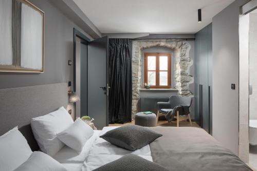 a bedroom with a bed and a chair and a window at Rialto Residence in Labin