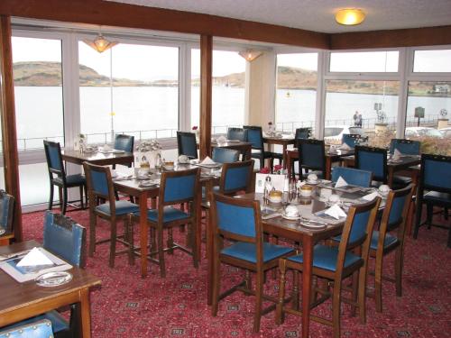オーバンにあるLancaster Hotelの水辺の景色を望むテーブルと椅子付きのレストラン