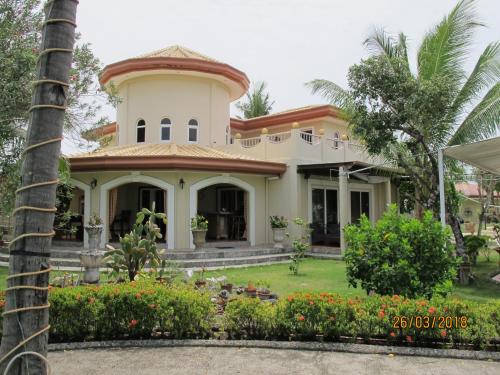 a house with a garden and a palm tree at Cabilao Sunset Dive & Beach Resort in Loon