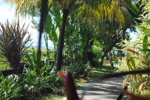 a path through a garden with palm trees and plants at Kori Maharani Villas & Resort in Keramas