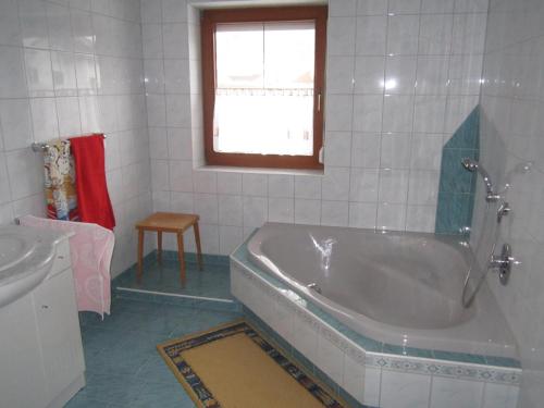 La salle de bains est pourvue d'une baignoire, d'un lavabo et d'une fenêtre. dans l'établissement Ferienhaus Martina, à Terfens