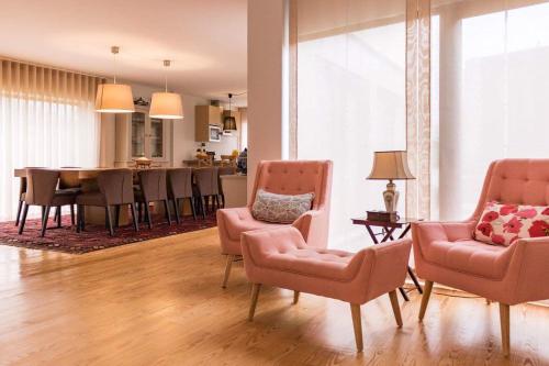 a living room with pink chairs and a dining room at Quinta de Alvarenga in Alvarenga