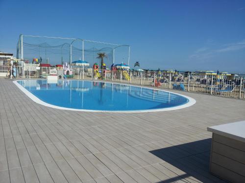 a swimming pool on a resort with chairs and the ocean at Hotel Ritter in Cattolica