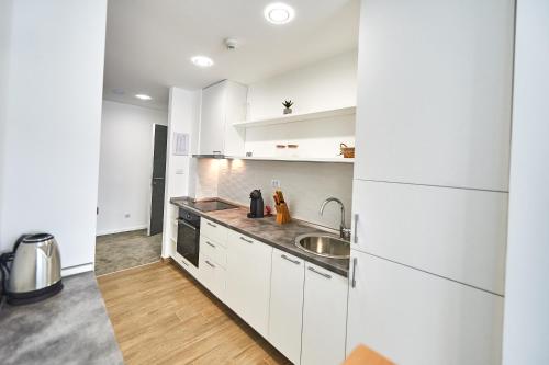 a kitchen with white cabinets and a sink at Perla Residence Hotel & SPA in Podgorica
