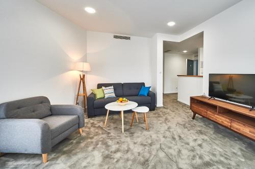 a living room with a couch and a table and a tv at Perla Residence Hotel & SPA in Podgorica