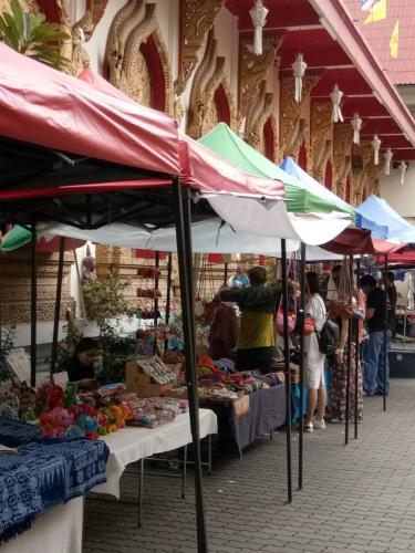 a market with a group of people standing in front of stalls at Kristi House in Chiang Mai