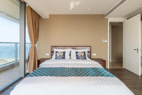 a bedroom with a large bed with a large window at Van-Pretty Residence Haitang Bay Sanya in Sanya