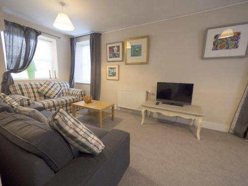 a living room with a couch and a tv at The Gallery Flat, 4 Tannage Brae in Kirriemuir