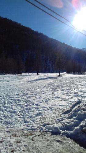 a field covered in snow with the sun in the background at Ca del nono in Pragelato