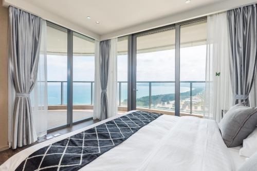 a bedroom with a large bed and large windows at Van-Pretty Residence Haitang Bay Sanya in Sanya