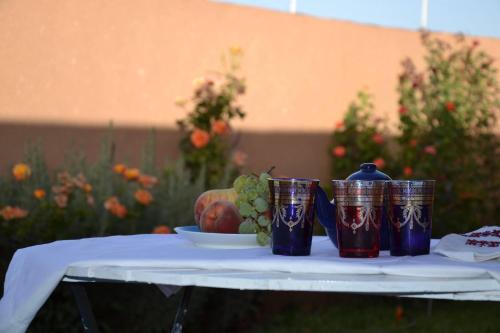 a table with three blue cups and a bowl of grapes at Ferme D"Hote Lala Fatima in Aïn Leuh