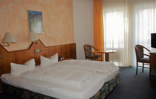 a bedroom with a large white bed and chairs at Hotel Schöne Aussicht in Gießen