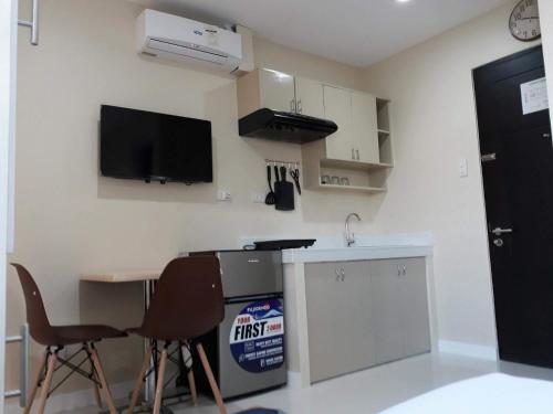 a kitchen with a table and two chairs and a tv at YulZ 516 at Cityscape in Bacolod