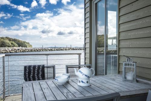 a wooden table with two chairs on a deck with the water at Im-Jaich Wasserferienwelt in Lauterbach