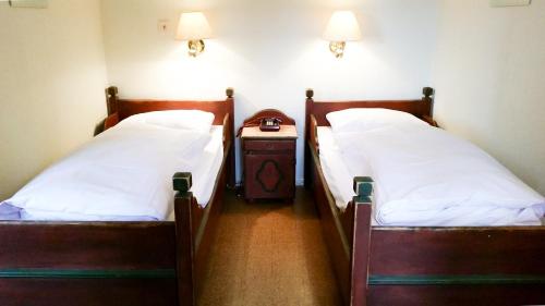 two twin beds in a room with a night stand at Rondane Høyfjellshotell in Mysusæter