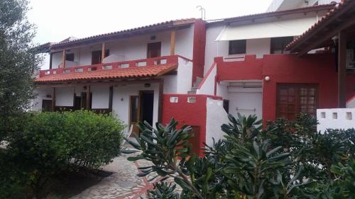a red and white house with bushes in front of it at Antikristo Rooms in Karteros