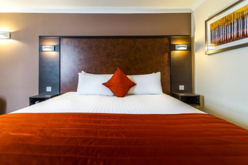 a bedroom with a large bed with orange and white pillows at Dragonfly Hotel Bury St Edmunds in Bury Saint Edmunds