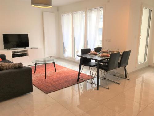 un salon avec une table, des chaises et une télévision dans l'établissement Cosy, à Annecy