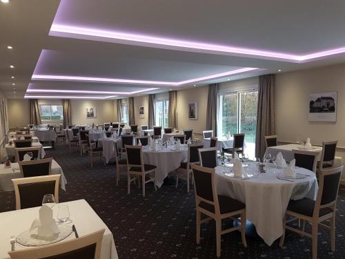 a dining room with white tables and chairs at Logis Hotel Restaurant de l'Abbaye in Ferrières